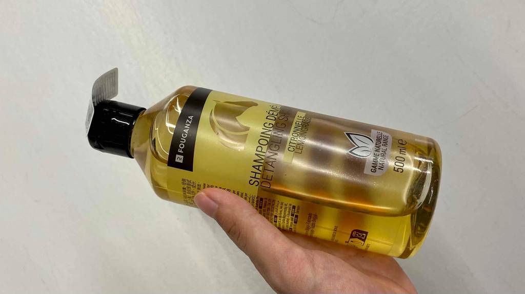 Pferdeshampoo im Test: Eine Hand hält eine Flasche vor einer hellen Oberfläche