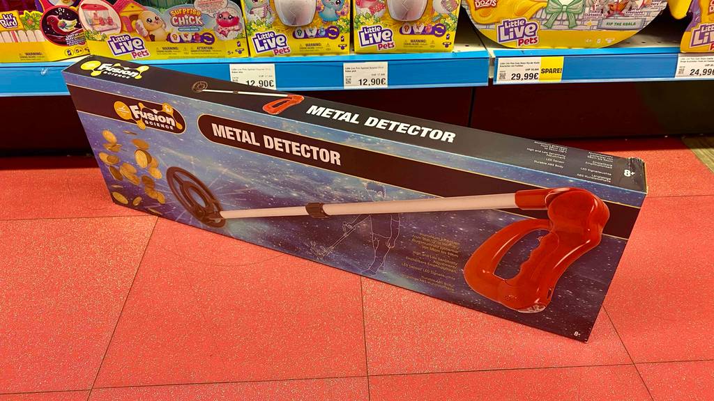 Metalldetektor für Kinder getestet: Ein verpacktes Gerät auf einem roten Boden vor einem Regal.