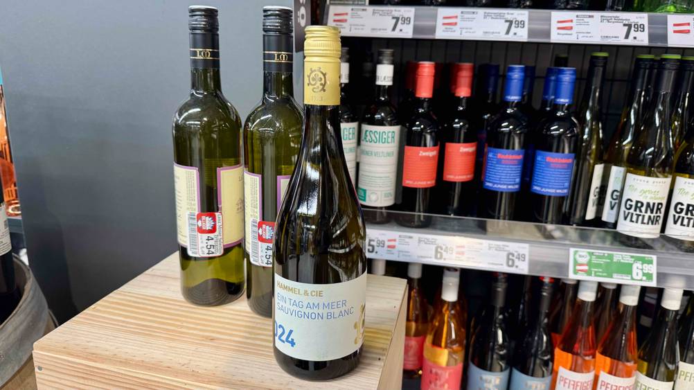 Der getestete Sauvignon-Blanc steht vor einem Weinregal.