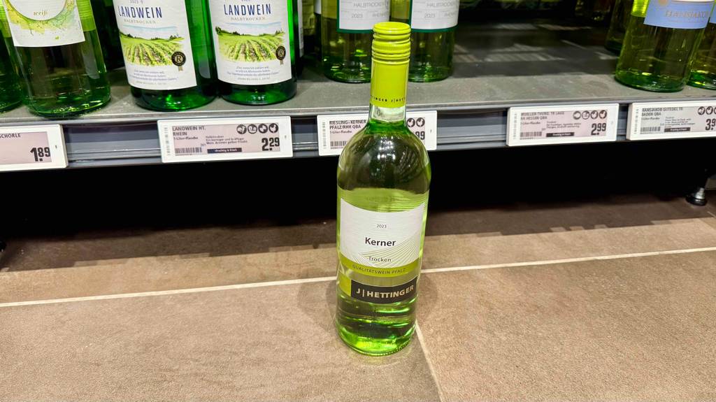 Test: Eine Flasche Kerner-Wein steht vor einem Regal worin sich weitere Weinflaschen befinden.