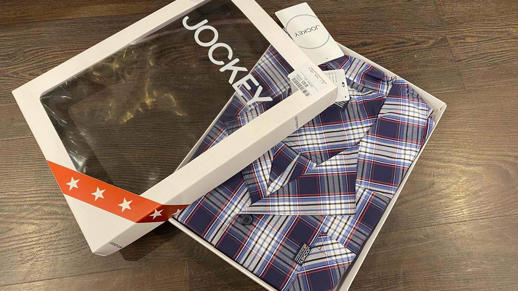 Ein gefalteter getesteter Pyjama für Herren in einem Karton mit geöfffnetem Deckel