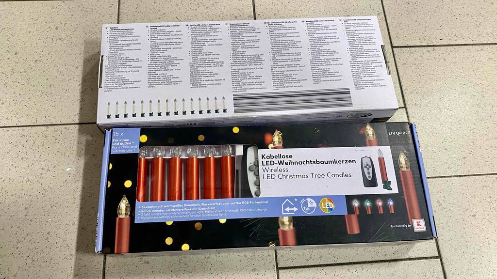 Kabellose Christbaumkerzen getestet: Zwei Packungen eine von vorne eine von hinten auf einem Fließenboden.
