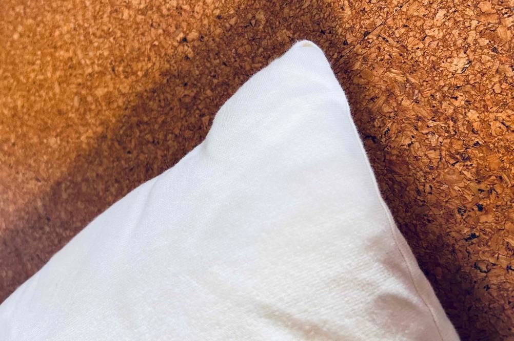 Kopfkissen 40 x 80 getestet: Detailansicht einer Ecke des Kissens auf eine Holzfläche.