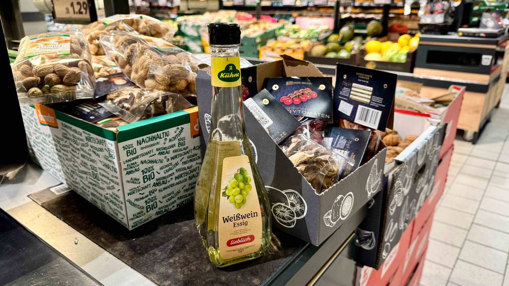 Test: Eine Flasche Weißweinessig steht in einem Geschäft neben anderen Lebensmitteln.