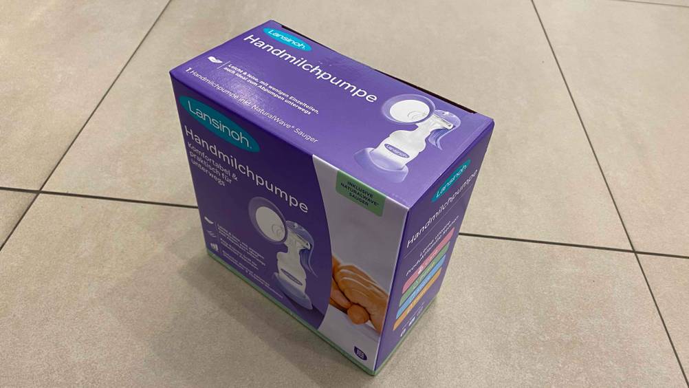 Handmilchpumpe im Test: Verpackung einer Handmilchpumpe im aufrecht stehenden Zustand auf einem Boden platziert.