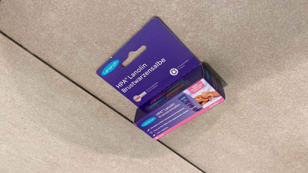 Brustwarzensalbe-Test: Verpackung von Brustwarzensalbe der Marke Lansinoh liegend auf einem Fliesenboden.
