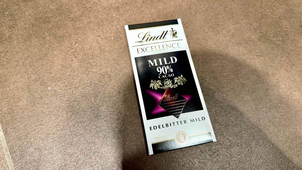 Eine getestete Tafel Lindt-Schokolade mit 90 % Kakaoanteil liegt auf einer grauen Fläche.