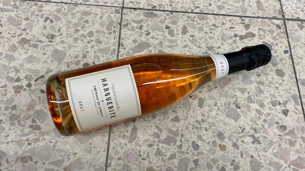 Auf einem Fließenboden liegt eine getestete Flasche Crémant