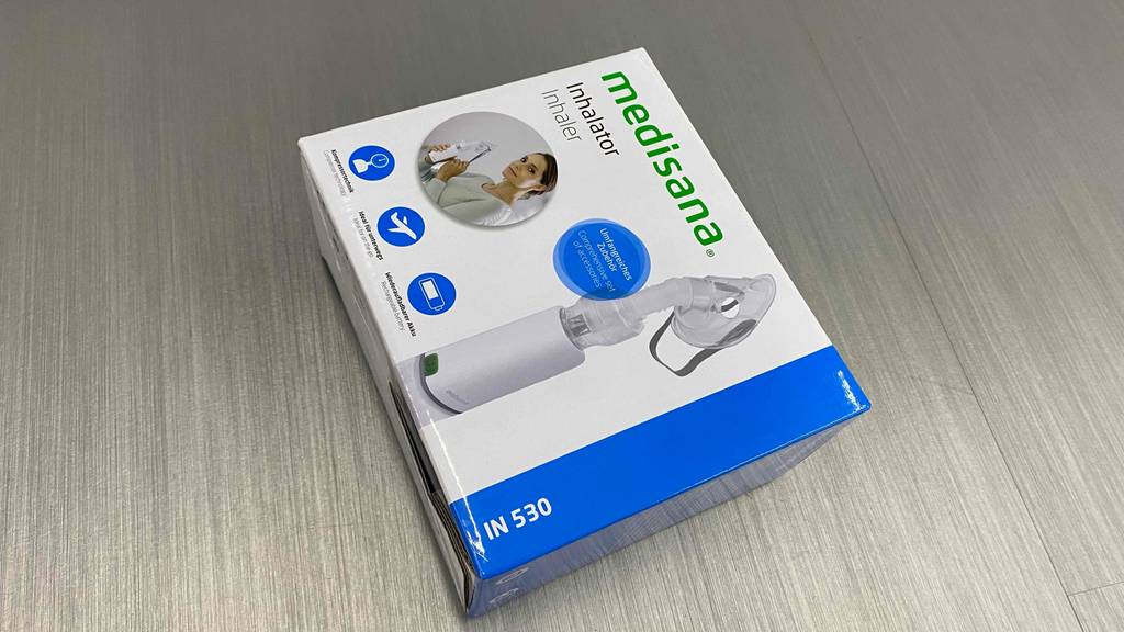 Ein getesteter Inhalator in seiner Verpackung liegt quer auf einem grauen Boden.