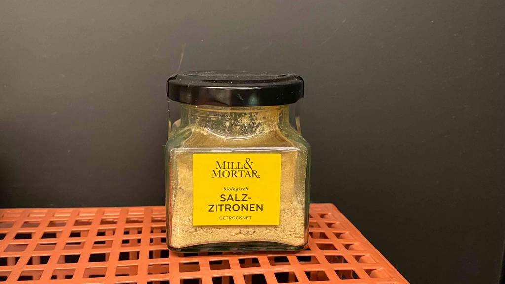 Ein getestetes Glas Salzzitronen auf einer orangenen Gitterfläche.