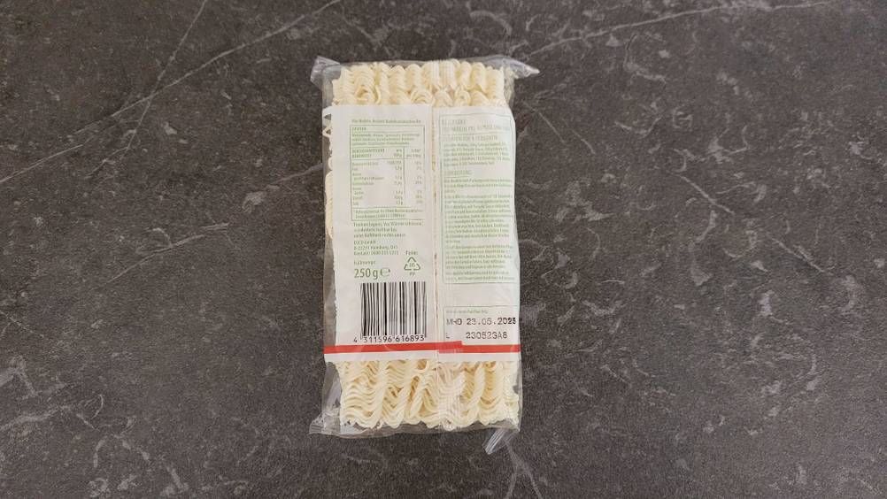 Rückseite einer Packung getesteter Mie-Nudeln auf einer dunklen Fläche.