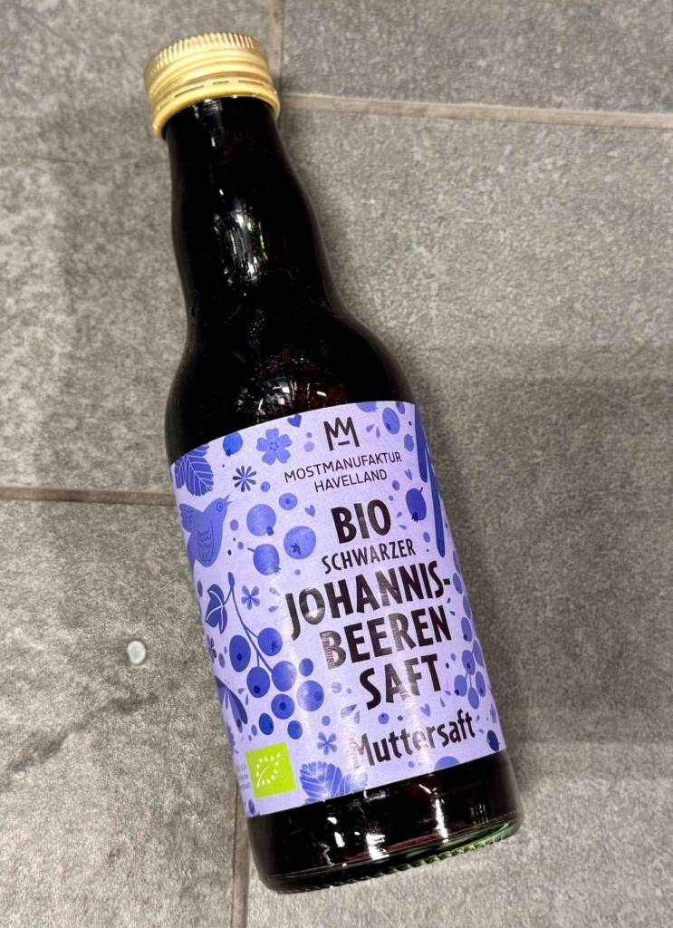 Detailansicht des violettfarbenen Etiketts auf einer grünen Glasflasche mit dem getesteten Johannisbeersaft.