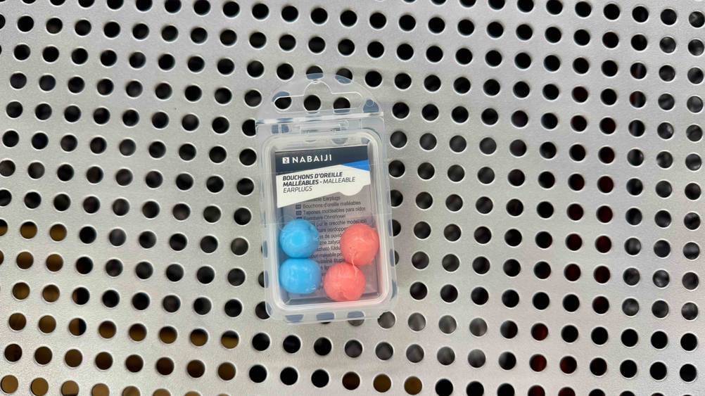 Die getesteten Silikon-Ohrstöpsel in blauer und roter Farbe liegen in der Verpackung auf einem Gitter.