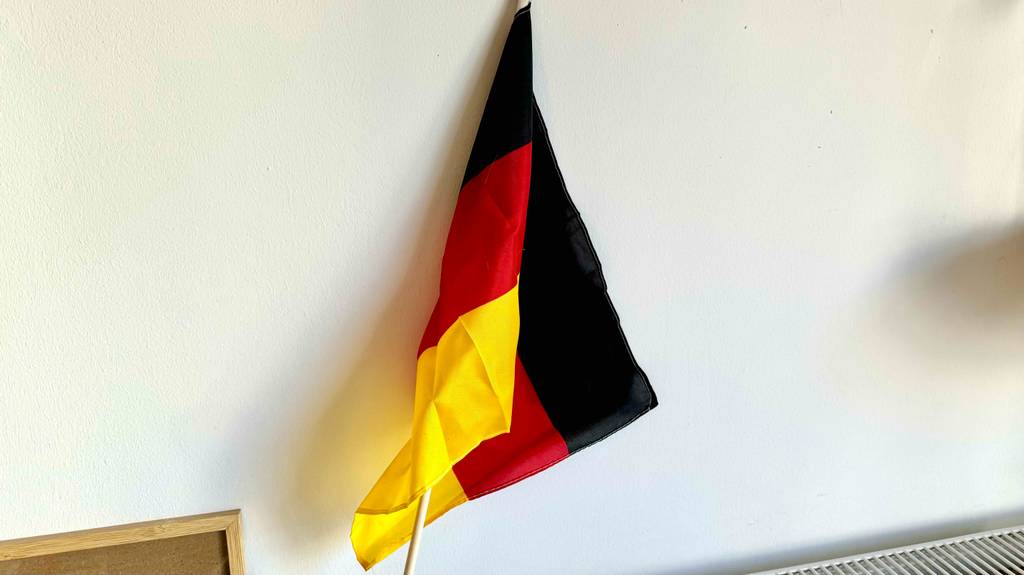 Deutschlandfahne im Test: eine Deutschlandfahne wird vor einer weißen Wand gehalten.