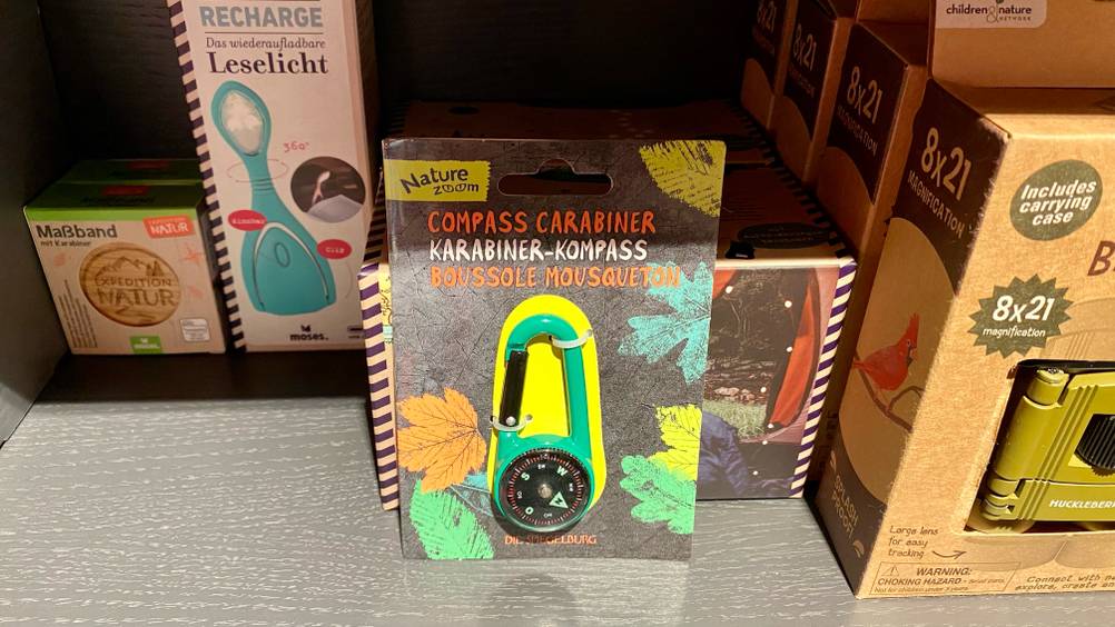 Ein getesteter Kompass in seiner Originalverpackung steht in einem Regal neben anderen Produkten.