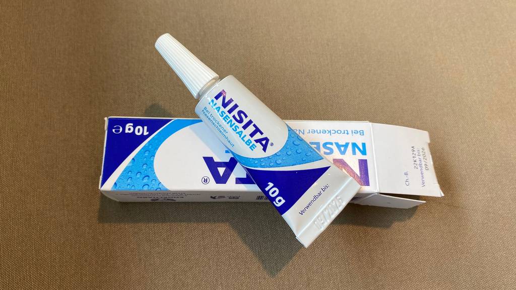 Nasensalben im Test: Eine Tube Salbe liegt auf ihrer Umverpackung auf einer hellen Oberfläche