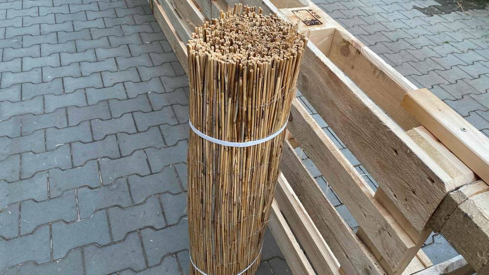 Schilfrohrmatte getestet: eine Schilfrohrmatte mit Kabelbinder zusammengebunden steht aufgestellt im Außenbereich.