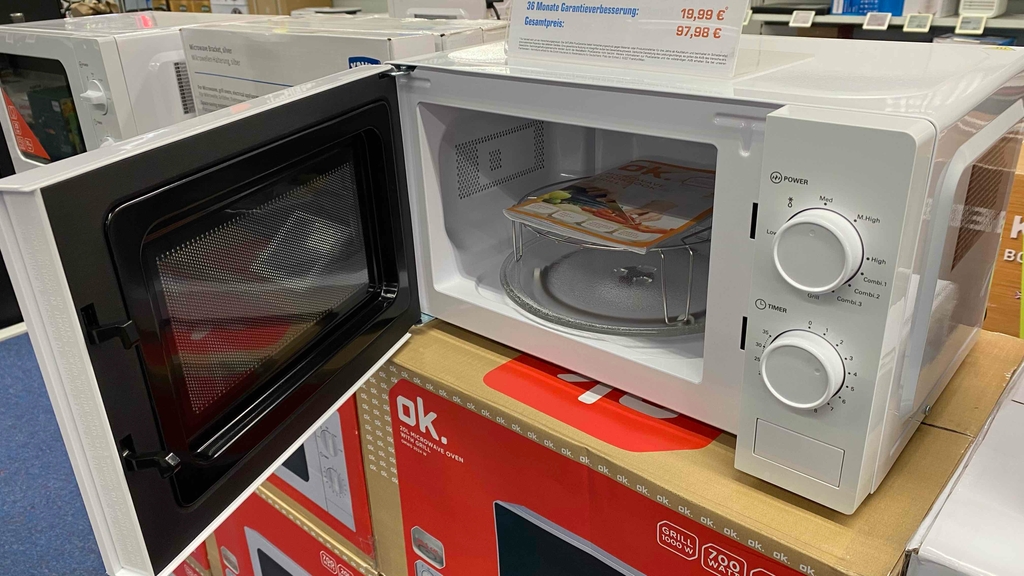 Eine getestete Mikrowelle mit Grill von ok. auf einem Karton mit geöffneter Tür.