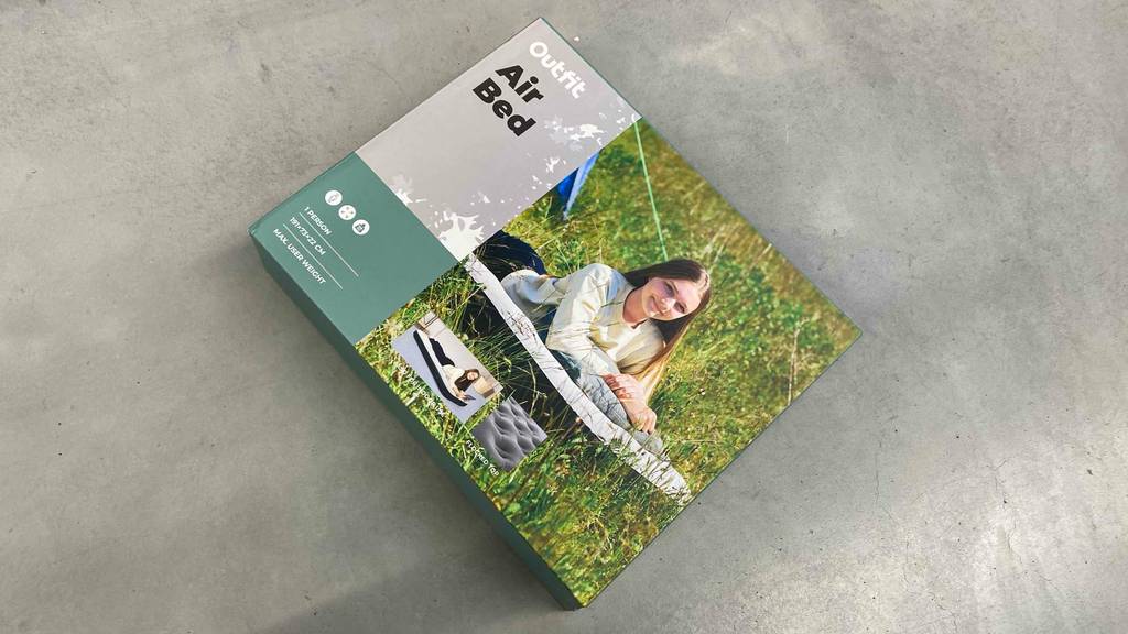 Auf einem Betonboden liegt ein getestetes Luftbett in seiner Originalverpackung.