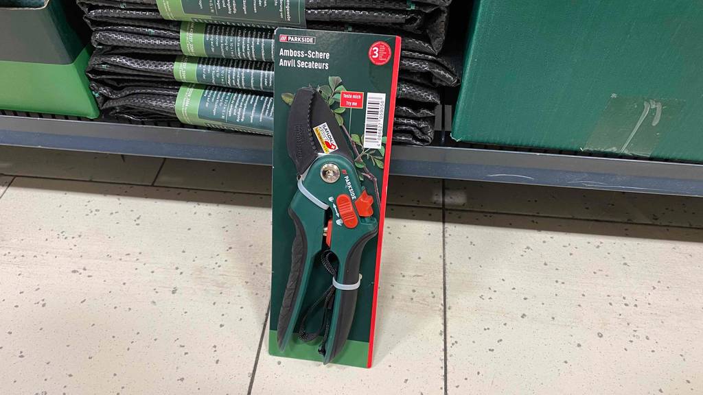 Amboss-Gartenschere getestet: Eine verpackte Schere steht angelehnt an ein Regal auf dem Boden