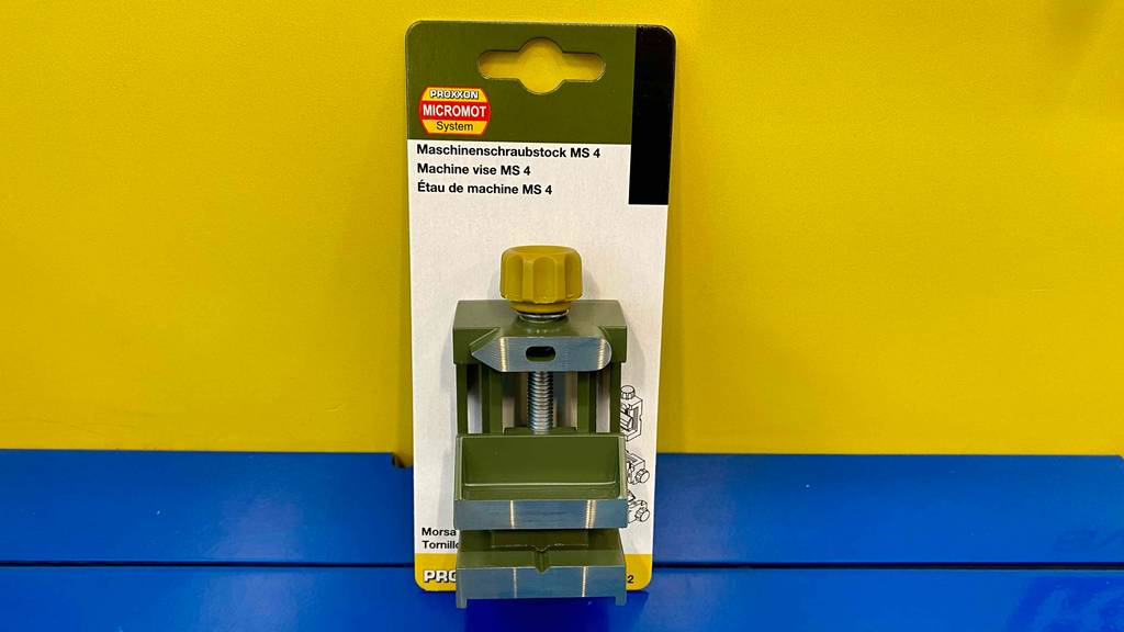 Maschinenschraubstock im Test: Maschinenschraubstock steht verpackt vor einer gelben Wand.