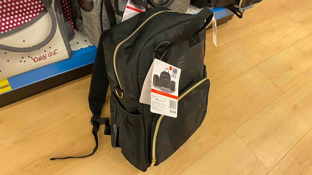 Ein getesteter Wickelrucksack von schräg oben auf einem Holzboden.
