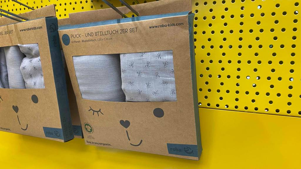 Eine Packung getesteter Pucktücher hängt vor einer gelben Wand.