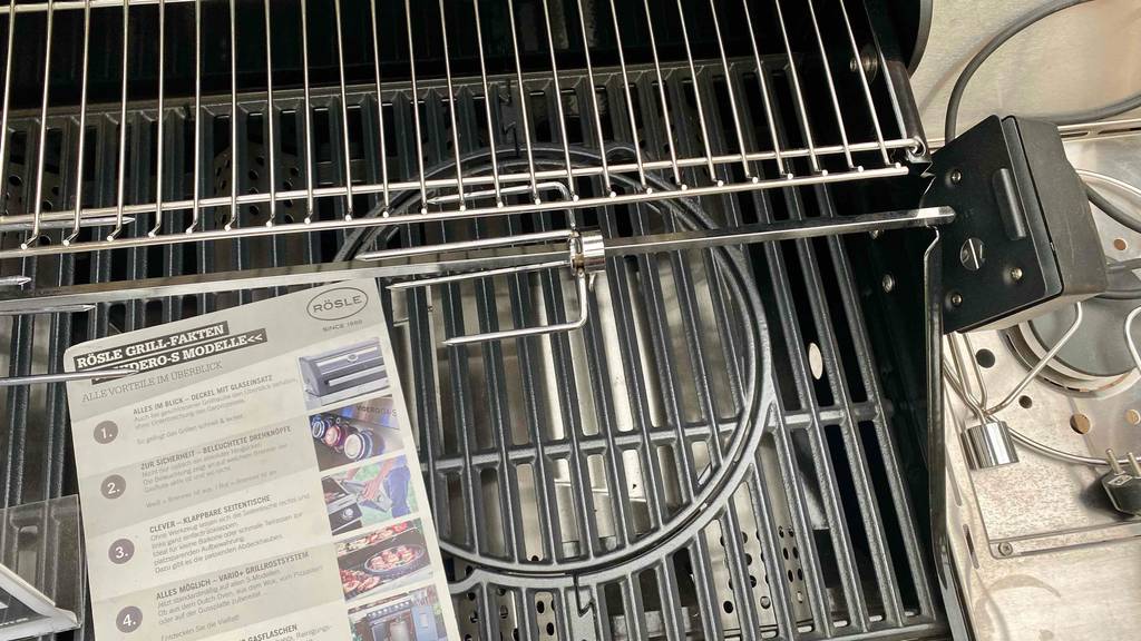 Rösle-Gasgrill-Test: Grillrost eines Rösle-Gasgrills im Fokus, mit Informationsbroschüre darauf liegend.