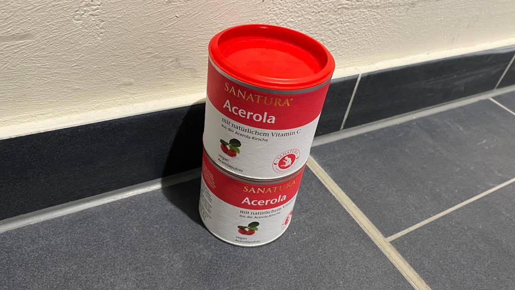 Acerola getestet: Zwei Dosen übereinandergestapelt auf einem grauen Fließenboden