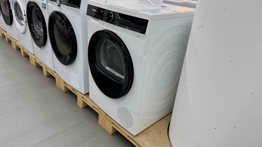 Der weiße Siemens-Wärmepumpentrockner im Test steht neben anderen Trocknern im Verkaufsbereich.