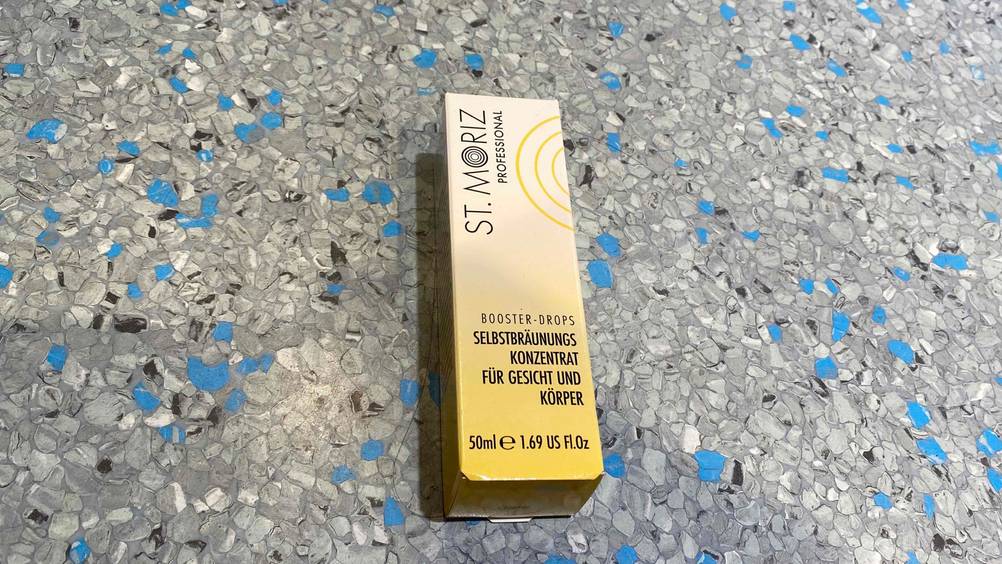Selbstbräuner Gesicht im Test: Eine Packung liegt auf einem Fließenboden