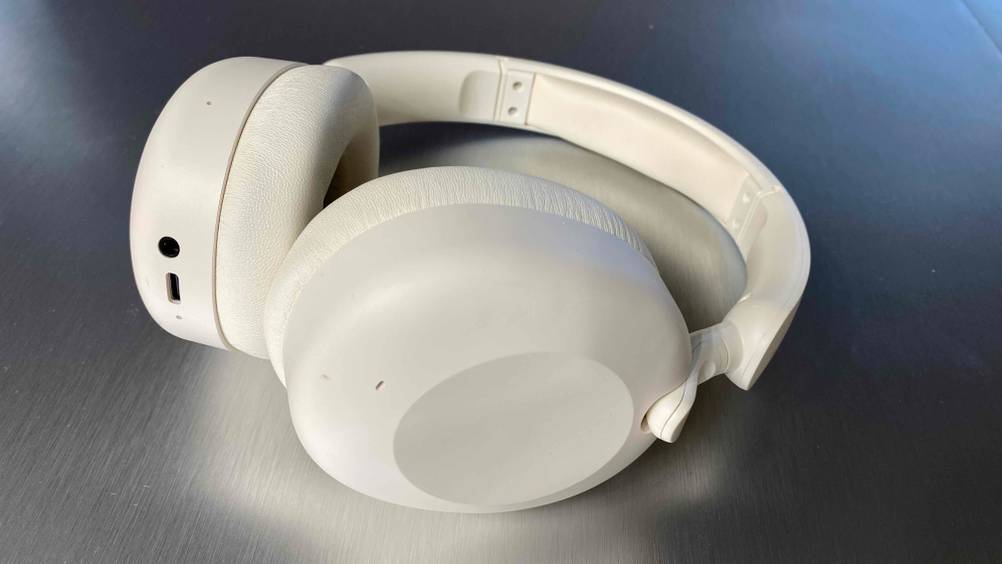 Auf einer glänzenden Oberfläche liegt ein weißer, getesteter Over-Ear-Kopfhörer.