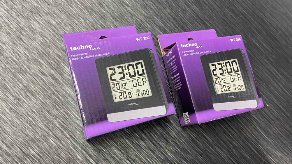 Funkwecker getestet: Zwei verpackte Geräte nebeneinander auf einer grauen Fläche.