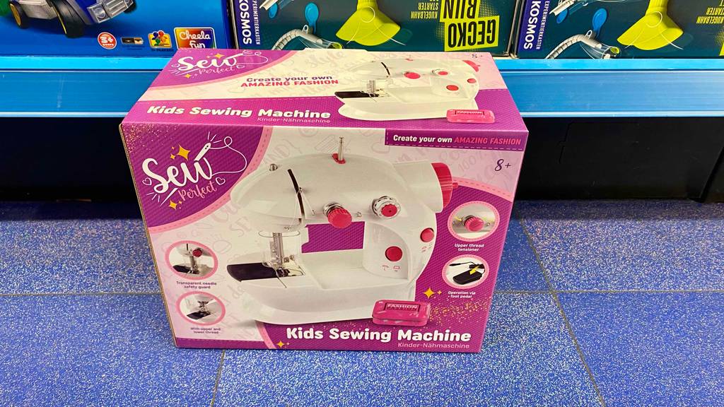 Vor einem Regal auf einem blauen Boden steht eine getestete Kindernähmaschine.