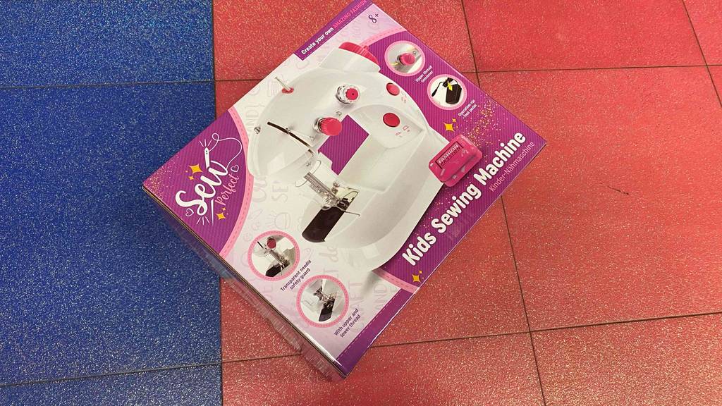 Kindernähmaschine getestet: Auf einem roten Boden liegt eine verpackte Kindernähmaschine.