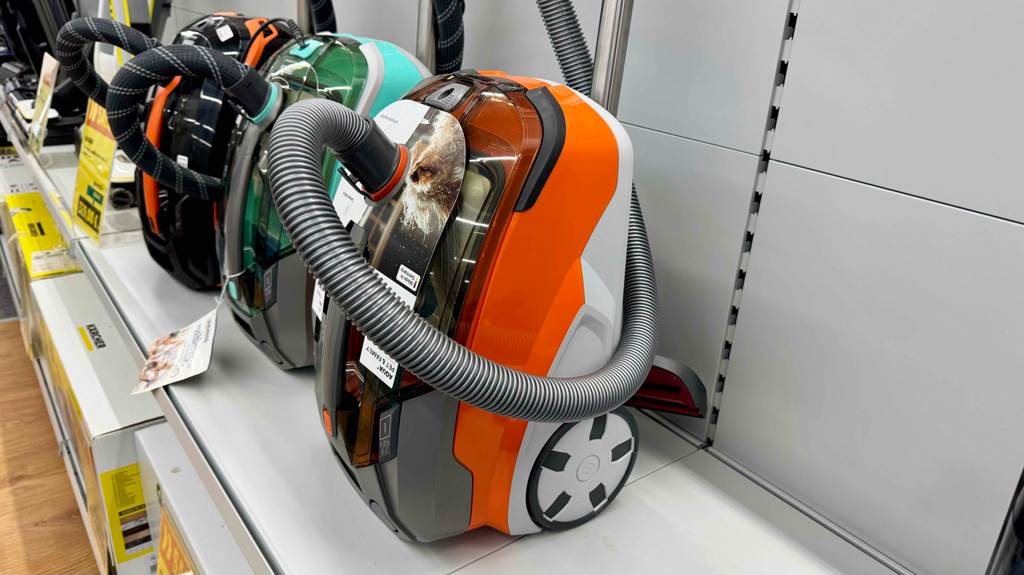 Getestet: Der Thomas-Staubsauger in Weiß-orange steht auf einem Ausstellungsregal vor mehreren anderen Staubsaugermodellen.