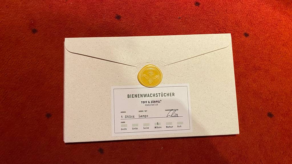 Ein getestetes Bienenwachstuch verpackt auf einer roten Fläche.