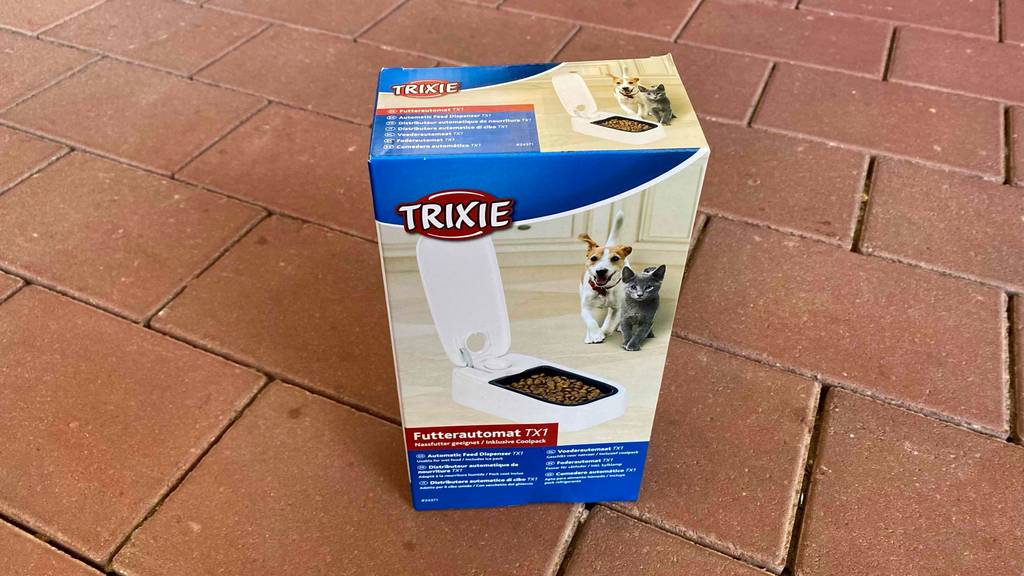 Futterautomat für die Katze-Test: Verpackung von Futterautomat mit weißem Modell darin steht auf einem Boden.