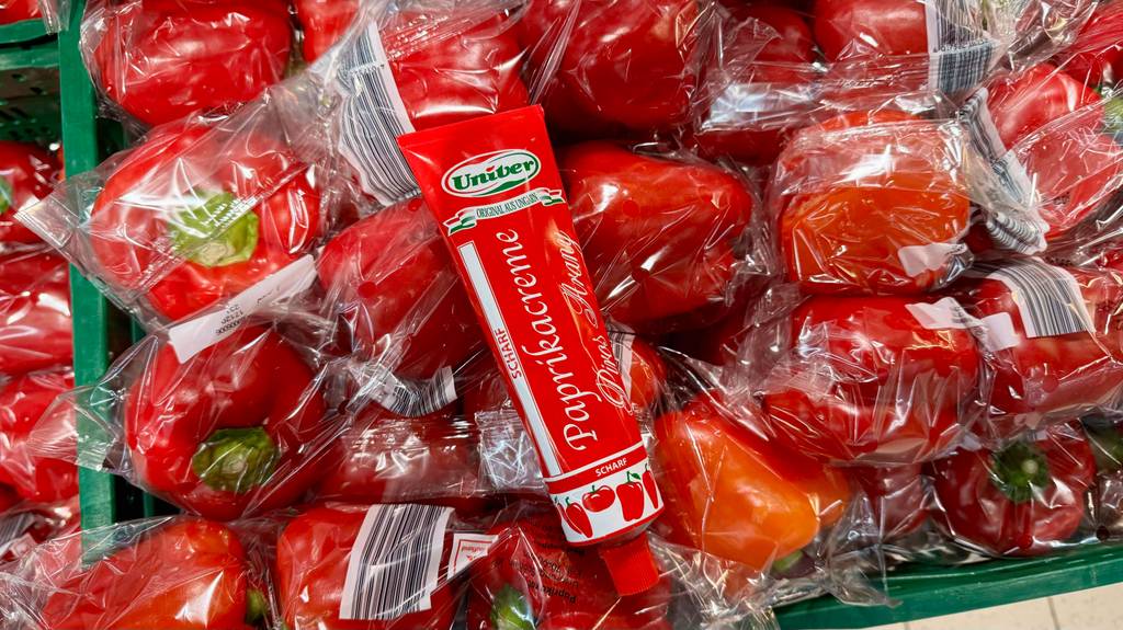 Test: Eine Tube Paprikapaste liegt auf frischen Paprika.