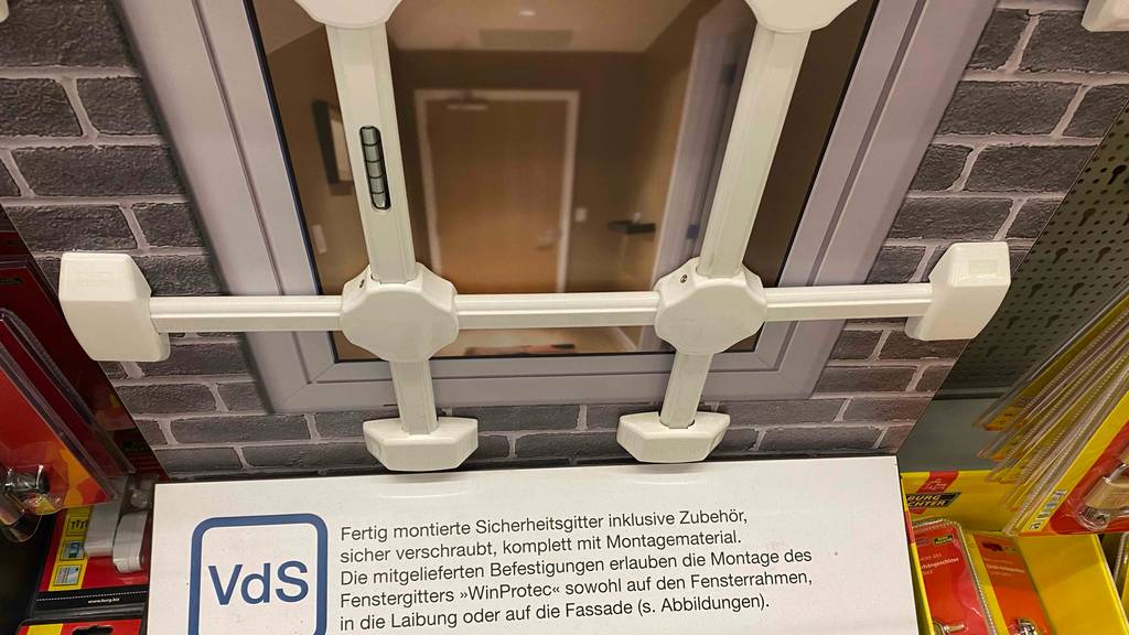 Fenstergitter getestet: ein weißes Fenstergitter ist in einem Geschäft ausgestellt mit Werbeschilld davor.