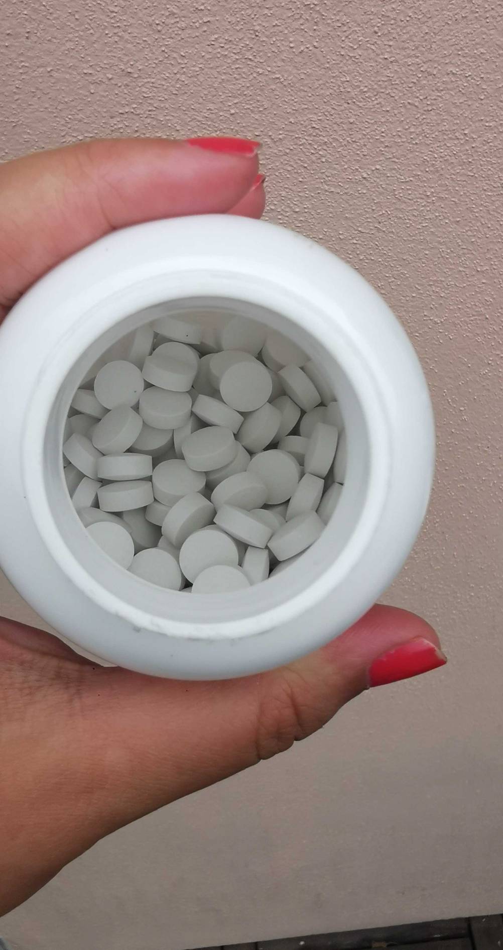 Eine Hand hält eine Dose der getesteten Zinktabletten ohne Deckel, im Inneren Tabletten.