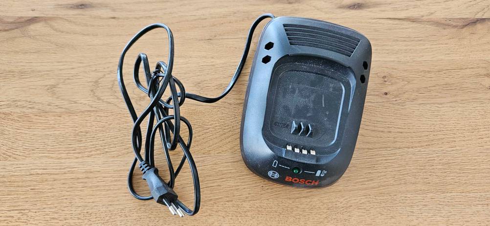 Bosch-Akkuschrauber im Test: Ladegerät eines Bosch-Akkuschraubers auf einer Holzfläche platziert.