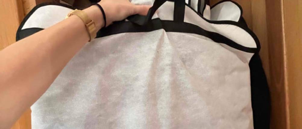 Kleidersack-Test: Hand, die einen Kleidersack im geöffneten Schrank hält