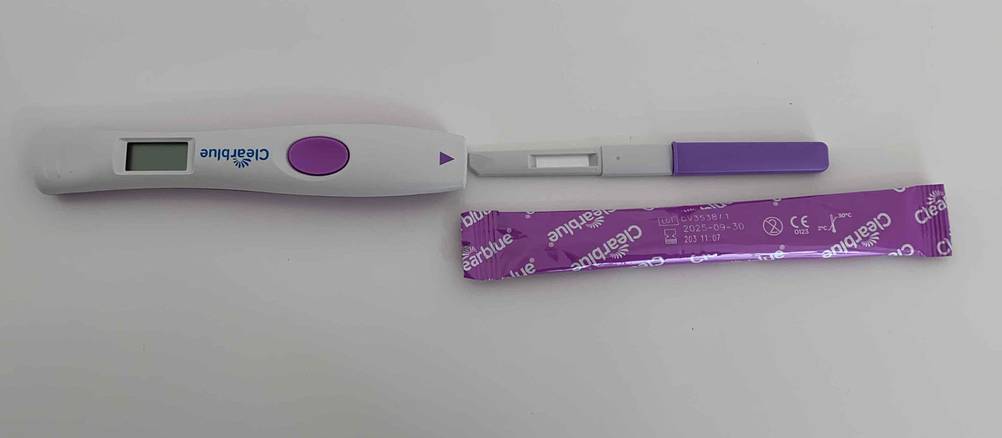 Ausgepackter und eingepackter Teststreifen von Ovulationstest und digitaler Stick daneben.