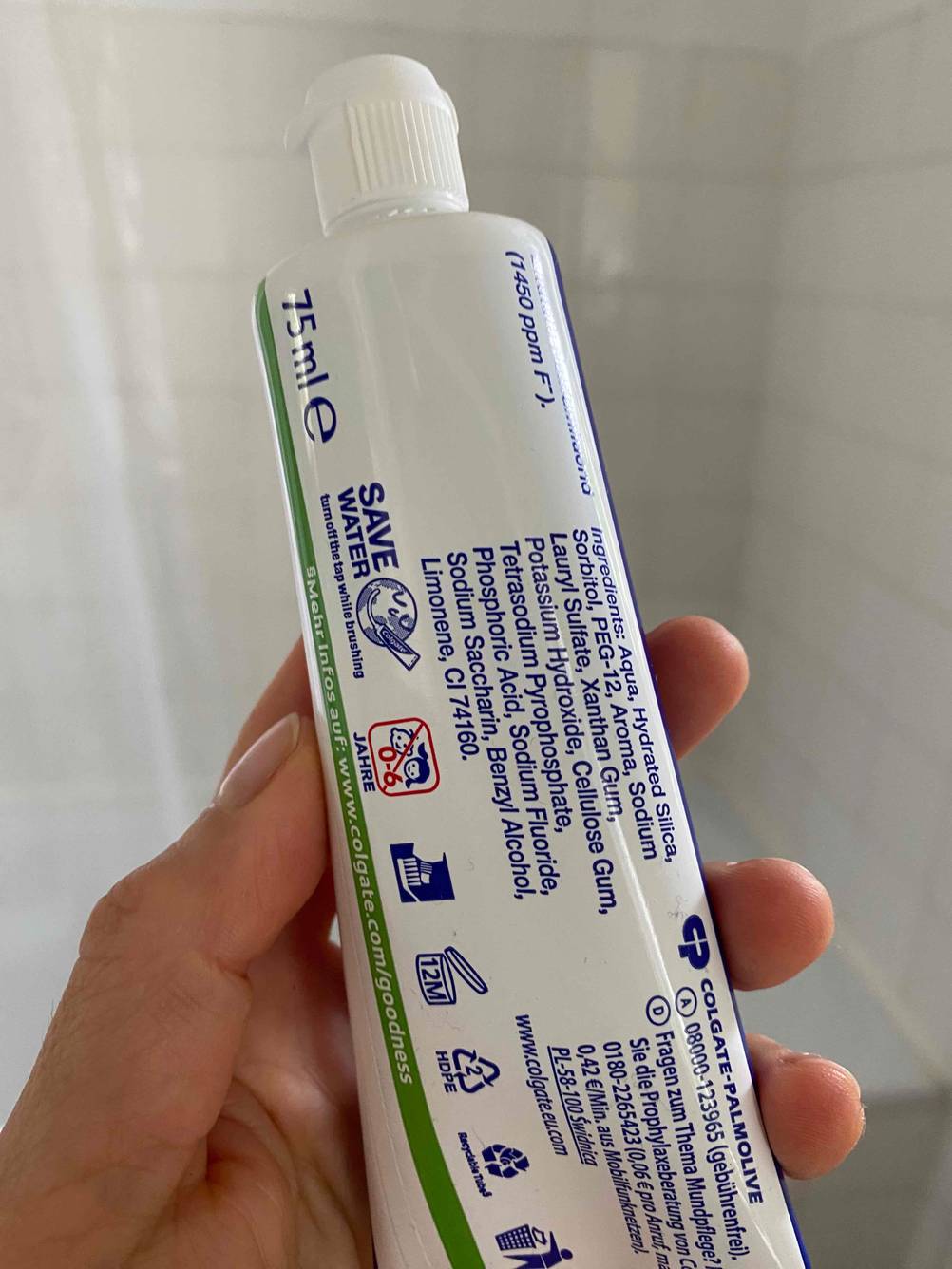 Hand hält eine Tube getestete Zahnpasta gegen Zahnfleischrückgang mit der Rückseite nach vorn.
