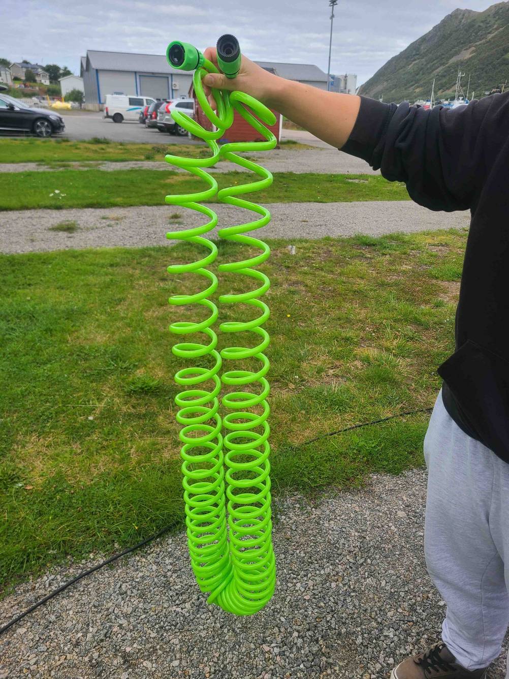 Der grüne Spiral-Gartenschlauch, der getestet wurde, wird in der Hand gehalten.