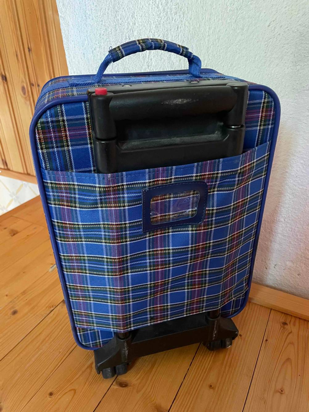 Kinderkoffer im Test: auf einem Holzboden steht ein Kinderkoffer mit der Rückseite nach vorne