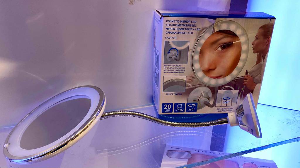 Im Test: Ein beleuchteter Kosmetikspiegel neben seiner Verpackung auf einem Glasregal.