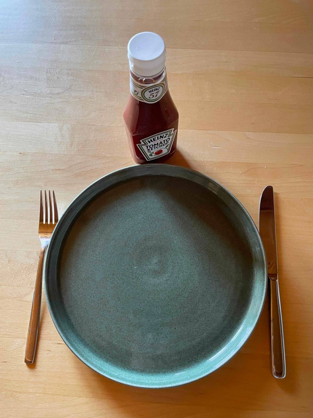 Ketchup Flasche auf einem Tisch mit Teller und Besteck.