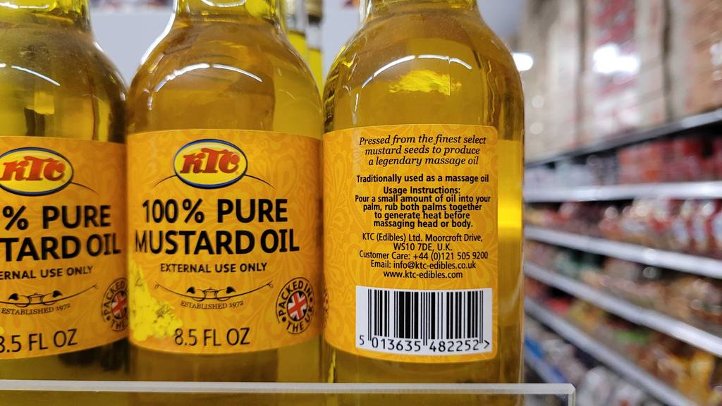 Senföl im Test: eine Flasche Senföl von der Rückseite ersichtlich steht neben anderen Senfölen in einem Regal.